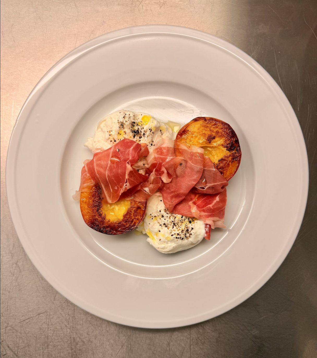 Burrata with grilled peach halves and thin slices of ham