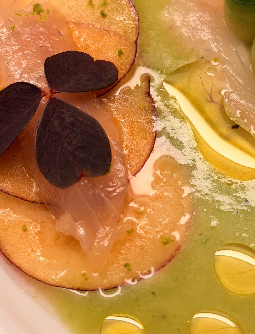 Close-up of plum slices with fish, oxalis leaf and drops of olive oil
