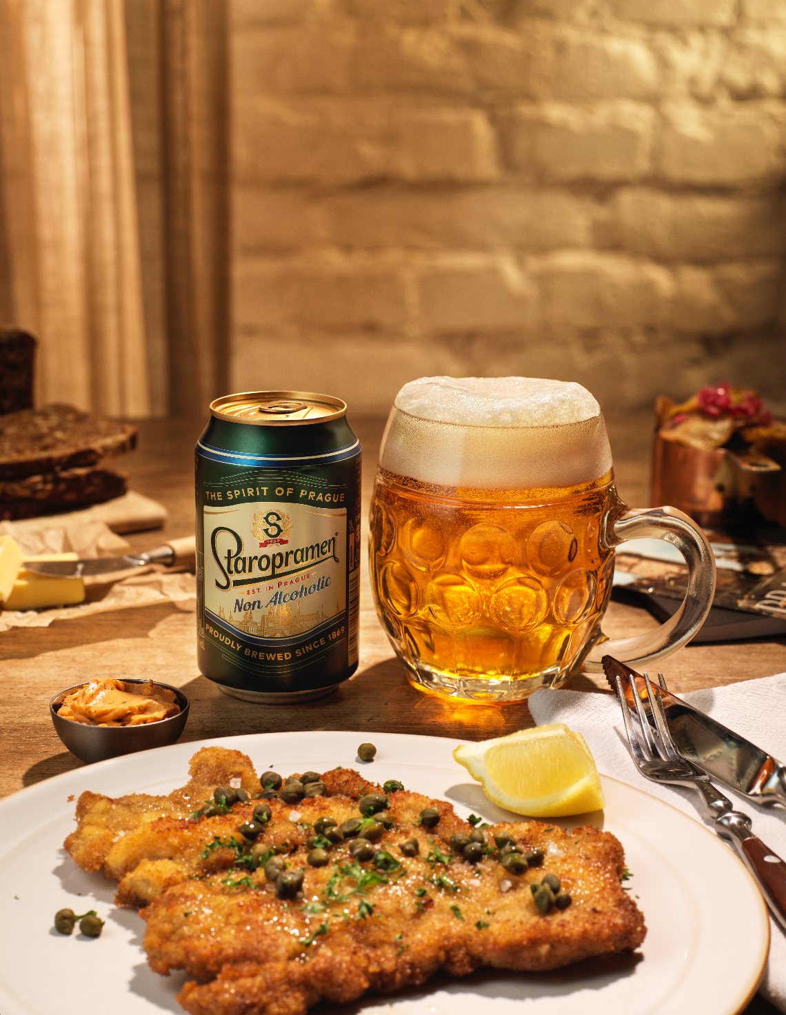 Staropramen can and beer mug behind a plate of schnitzel