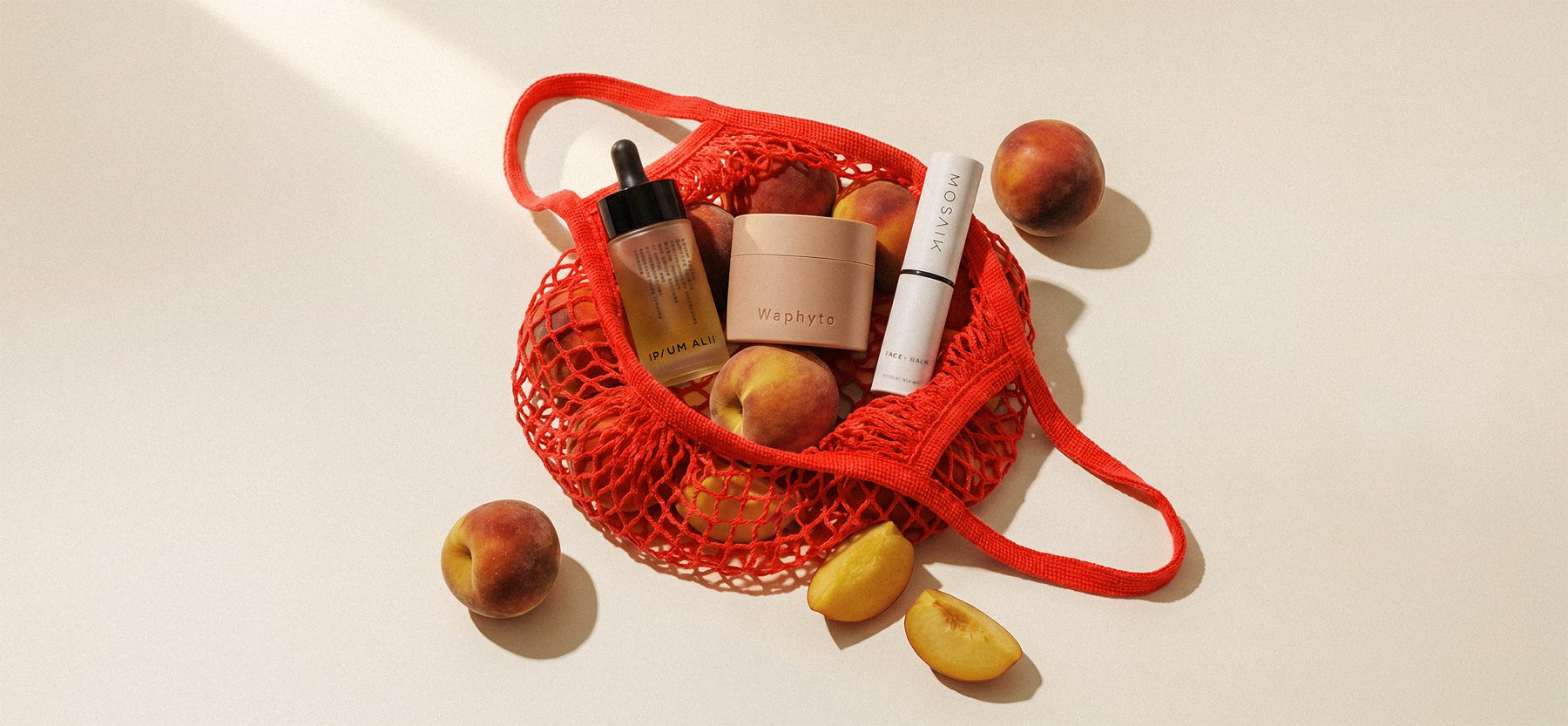 Red mesh bag of peaches with YAY YAY skincare products